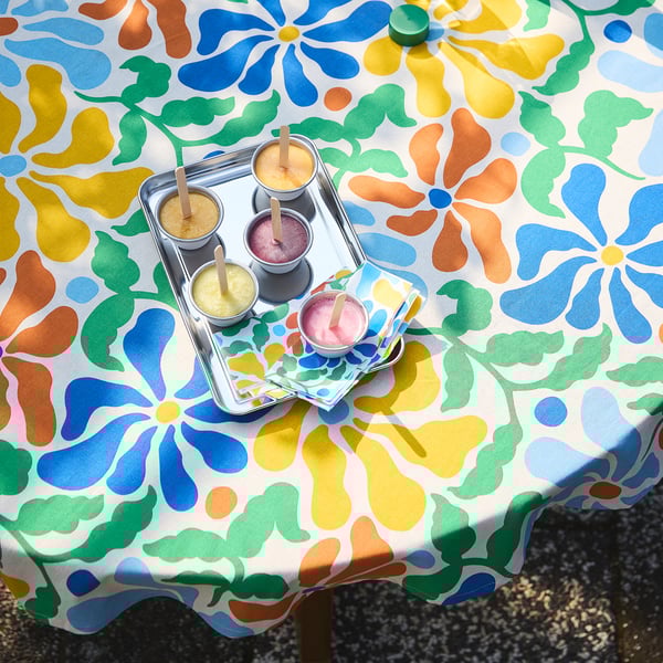 Bright, patterned tablecloth with four cups on a tray, holding colorful drinks. Ideal for summer meals, coordinating with PILLERSTARR series.