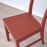 Red wooden chair with a solid frame and angled backrest, placed on light wooden flooring.