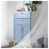 Light blue PLATSA storage cabinet with drawers and doors, white handles, decorated with flowers and a lamp.