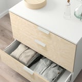 White and light wood PLATSA chest with drawers open, showing neatly folded clothes inside.