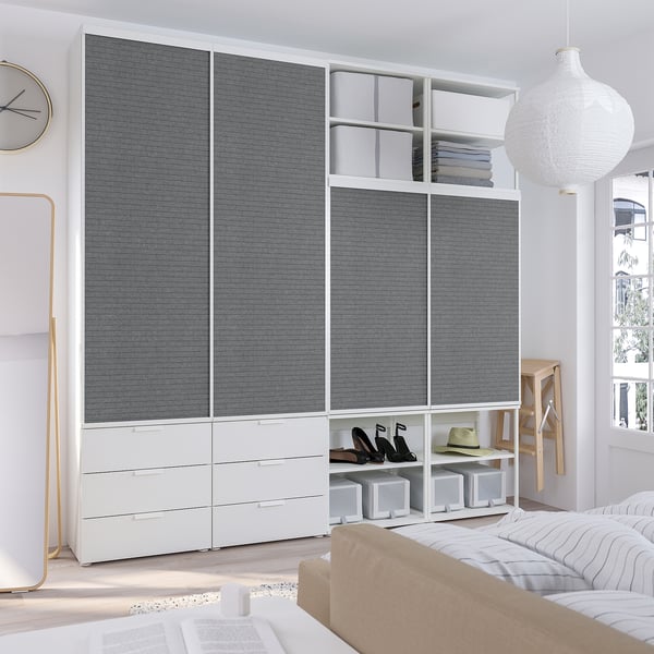 Modern bedroom with PLATSA wardrobe, white dresser, gold mirror, pendant lamp, & cosy striped bed.
