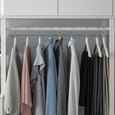 Closet with hangers holding clothes in white hooks, organized on adjustable PLATSA frame.