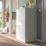 Modern hallway white PLATSA storage unit with gray door, taller than nearby coat rack, near grey door.