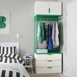 Modern bedroom with white-green PLATSA wardrobe, striped bedding, ample storage.