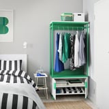 A bedroom with a green PLATSA wardrobe, holding clothes, and a striped bed.