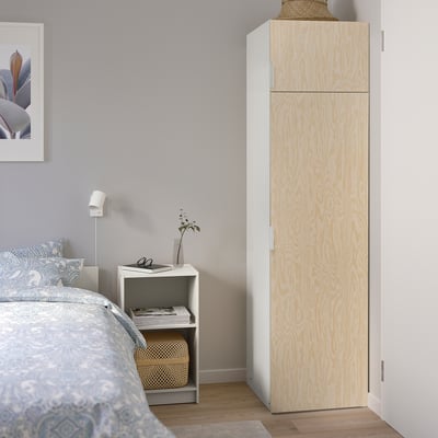 Minimalist bedroom with light wood PLATSA wardrobe, white nightstand, and blue patterned bedding against grey wall.