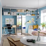 Modern home office with wooden desk, black chair, bookshelves, sofa bed, dining table, and large window.