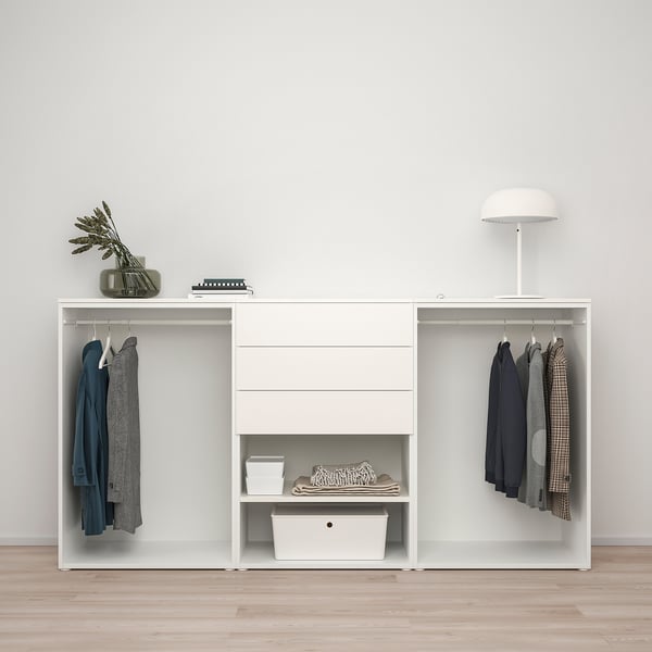 Modern white wardrobe with hangers, shelves, and lamp. Organized with clothes and decorative vase.