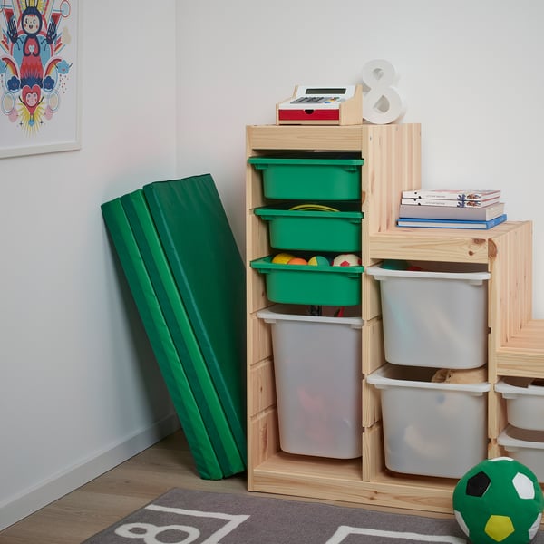 Childs play area with wooden toy storage and green gym mat. Bins hold toys, books, and a slide for play.