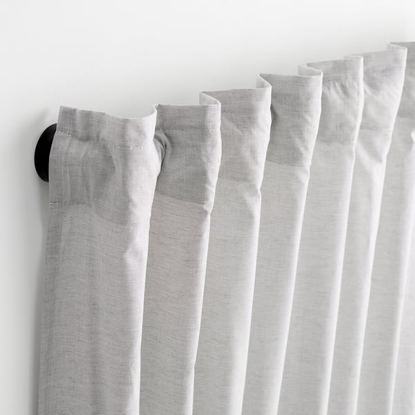Black curtain rod with powder coating, holding sheer curtains, two wall fittings visible on left and right ends.