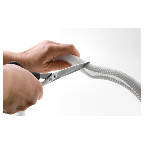 Person holding scissors cutting white cable tidy.