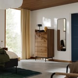 Bedroom with wooden dresser, four drawers, metal legs, and mirror. Soft curtains by window, rug on floor.