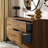 Wooden chest with 6 drawers, black metal legs, and blue interior. Top displays a lamp and a yellow vase.