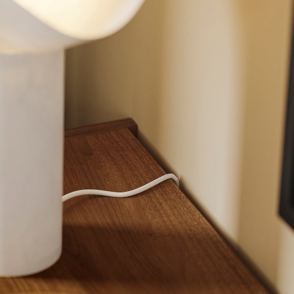 A wooden tv bench with a white cable management clip on the back, helping to keep cords organized and tidy.