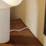 A wooden tv bench with a white cable management clip on the back, helping to keep cords organized and tidy.