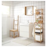 Minimalist white bathroom featuring RÅGRUND bamboo chair, shelf, and towel rack, offering multifunctional space-saving design.