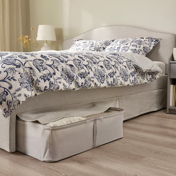 Neutral-tone upholstered bed with gray headboard, blue and white bedding, and under-bed storage. Easy to clean and provides storage.