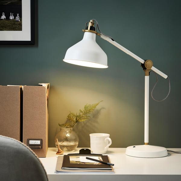 RANARP lamp illuminates workspace, lighting a notebook and plant.
