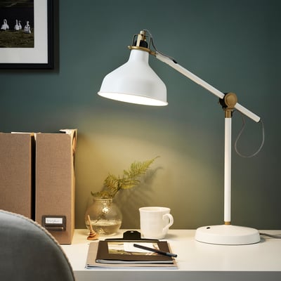 RANARP lamp illuminates workspace, lighting a notebook and plant.