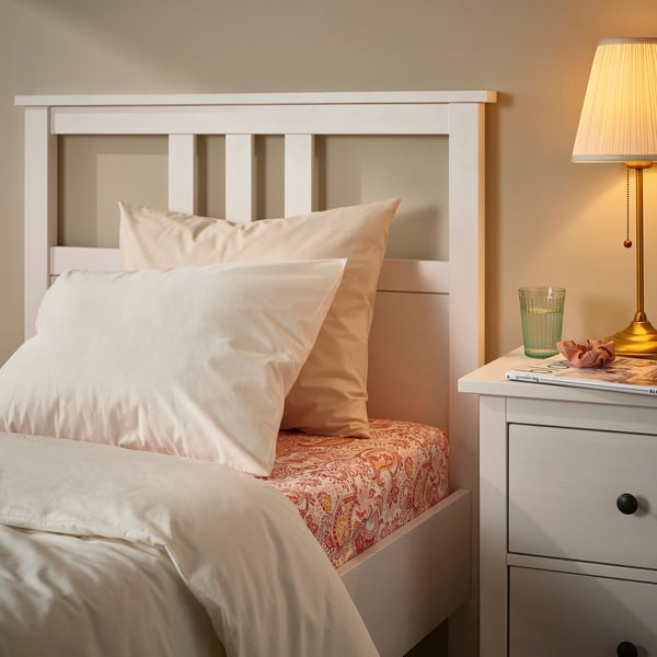 Bed with white RODGERSIA paisley sheet set. Quartz color, soft fabric, fitted design. Nightstand with lamp beside.