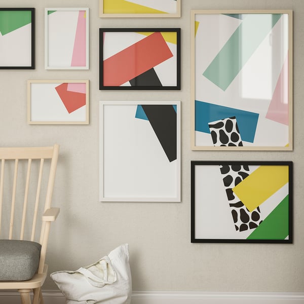 Gallery wall with abstract art, large RÖDALM frame, chair with cushion.
