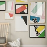 Gallery wall with abstract art, large RÖDALM frame, chair with cushion.