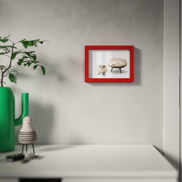Red-framed picture on gray wall, with modern decor and green vase.