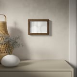 Wooden frame with abstract art on textured wall, dried flowers in wicker basket.