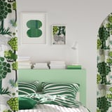 Bedroom with green bedding and wall art. RÖDALM picture frames above bed, smaller than walls.