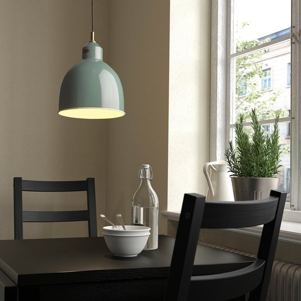Modern kitchen corner with teal RÖDFLIK pendant lamp, casting light over table with chairs, plant, and window.