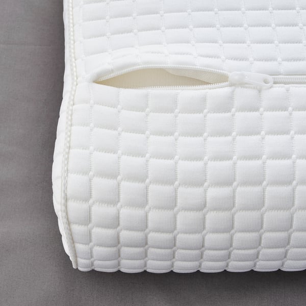 A close-up of a premium pillow with a textured, quilted white cover. It a zipper opening, indicating removable padding for easy washing.
