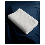 White ergonomic pillow on dark blue bedding, diamond-patterned design.