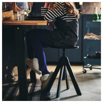 A black RUDSTORP stool with a round seat, adjustable height, and tripod legs. Modern and sturdy design.