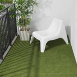 Small white chair on green artificial grass balcony with bamboo plant.