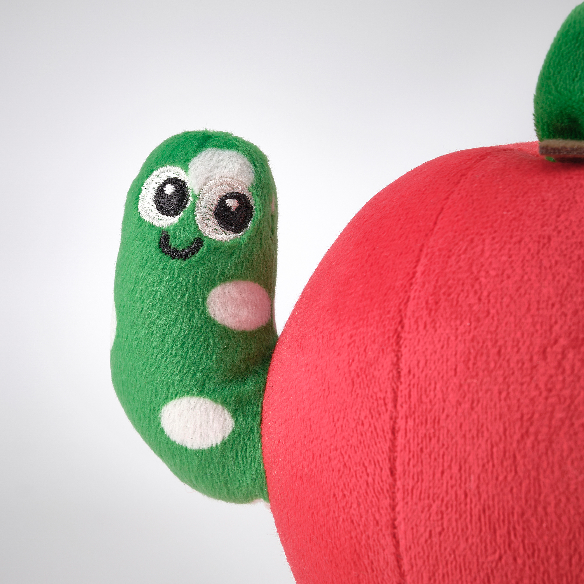 Soft toy apple with green worm peeking out, high-quality materials, cute design.