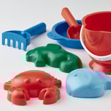 Beach toys: crab, fish, dinos, rake, buckets, and spade on white surface.
