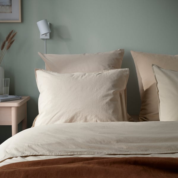 Beige velvet cushion on bed; soft, stylish with zipper; green wall, white light.