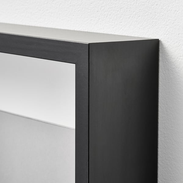 Black picture frame with clear plastic cover, good quality, on a white wall.