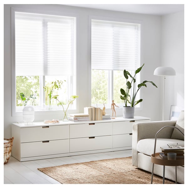 Modern living room with white furniture, plants, and SCHOTTIS light-diffusing blinds on windows.