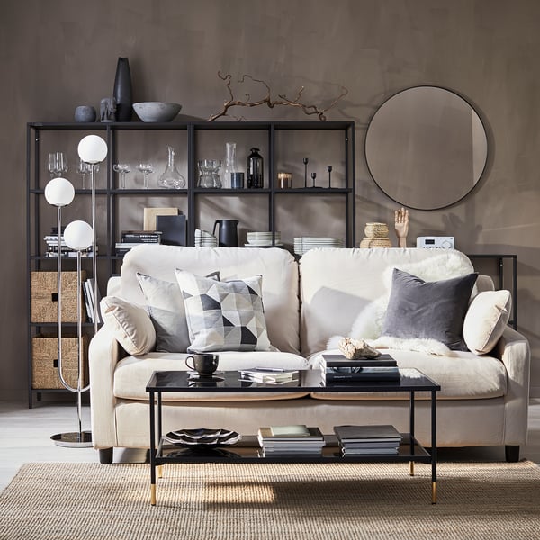 Modern living room with cream sofa, black coffee table, stylish lamp, books, and decorative items.