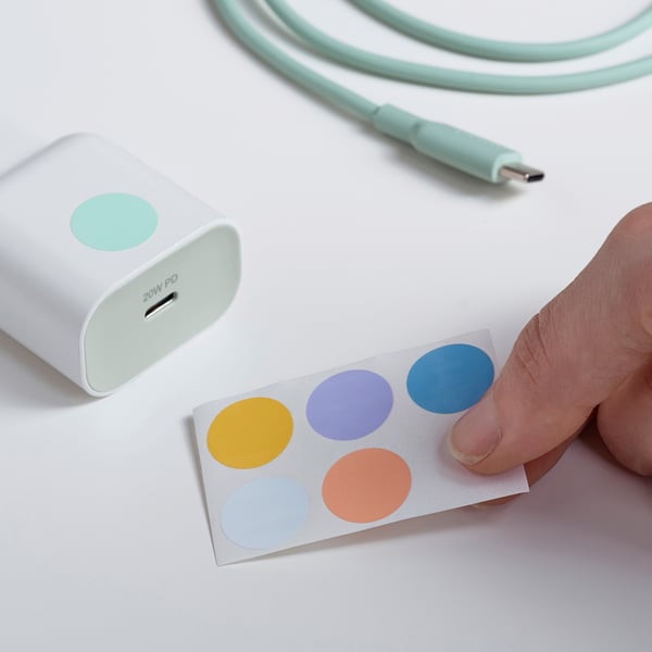 Person attaching colorful sticker to 20w usb-c charger, next to a mint green charging cable.