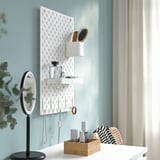 Wall-mounted SKÅDIS pegboard organizes jewelry, beauty items with shelves and hooks.