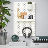 Wall-mounted storage panel with shelves, plant, decoration, and headphones. Organizes small items neatly.