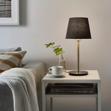 Cozy living room with SKAFTET lamp, couch, plant, and blanket.