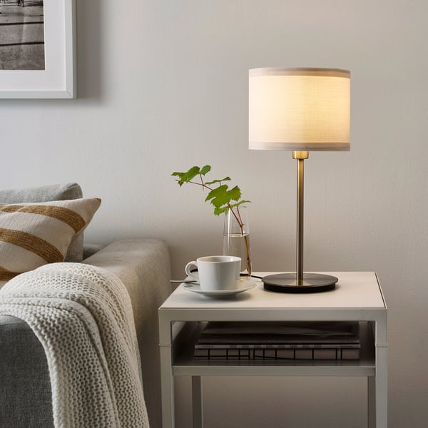 Cozy living room with striped pillow couch, warm lamp, mug, and plant.