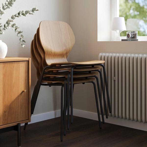 Stacked wooden chairs with metal legs near a wooden cabinet and radiator.