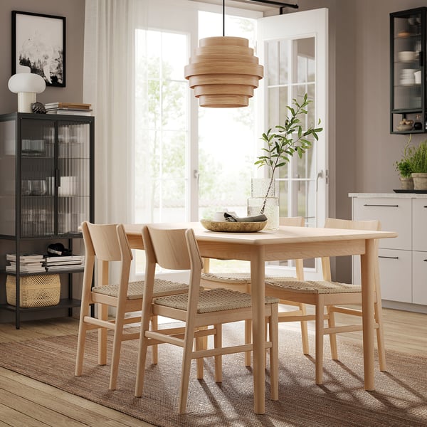 A modern light-brown wooden dining set with four chairs and an extendable table, inspired by scandinavian design.