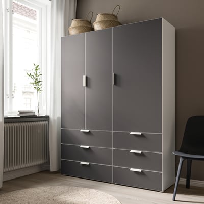 Modern grey SKATVAL cabinet with 3 drawers and 2 doors, mounted on feet, placed near a window.