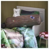 SKOGSDUVA: tree trunk-shaped pillow with insects on bed, white wall.