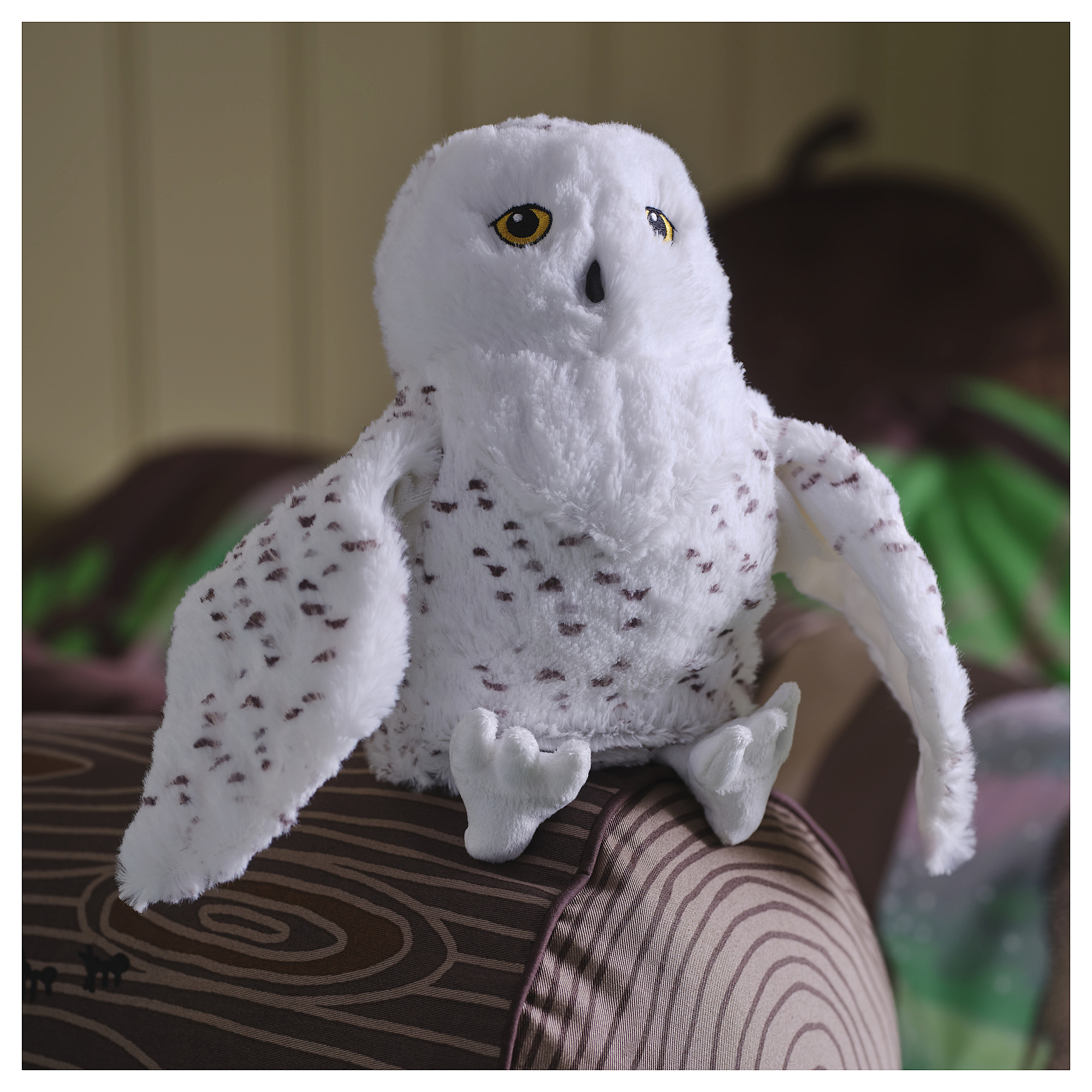 Soft white SKOGSDUVA owl toy sits on a cushion. Large, round eyes, small brown spots. Size similar to a hand.